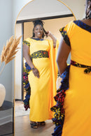 Person in a bright yellow dress with floral patterns, standing in front of a mirror.